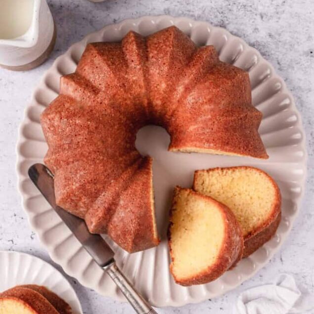 Freshly baked vanilla bundt cake with slices served on an elegant white platter. Perfect for desserts or teatime.