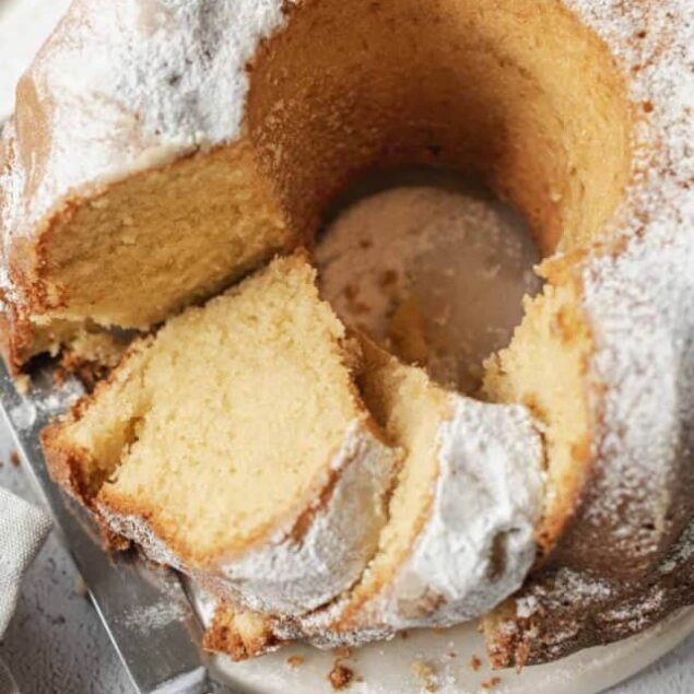 Fluffy homemade bundt cake with powdered sugar topping, sliced for serving.
