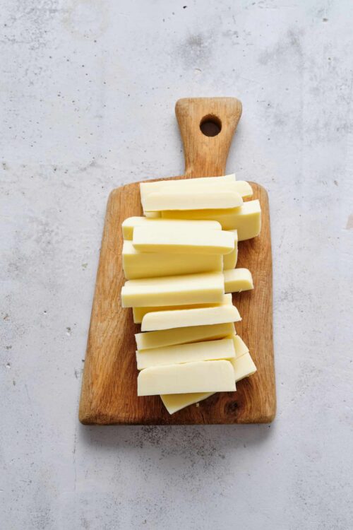 Sliced white cheese on wooden cutting board for baking or cooking recipes.