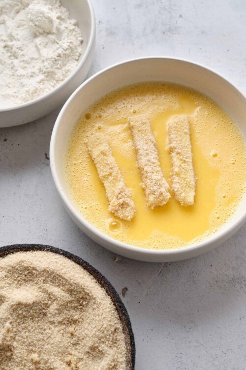 Breadcrumbs-coated fish fillets dipped in beaten eggs and flour, ready for breading and cooking.