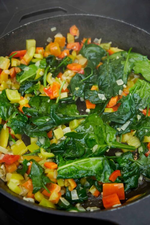 Sautéed colorful chopped vegetables in a black skillet, fresh and healthy cooking ingredients.