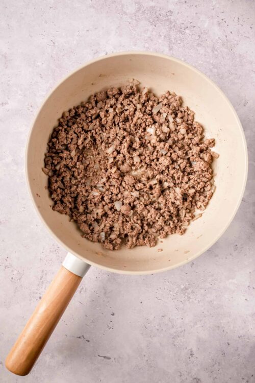 Minced cooked beef with onions in a beige cooking pot for hearty recipes.