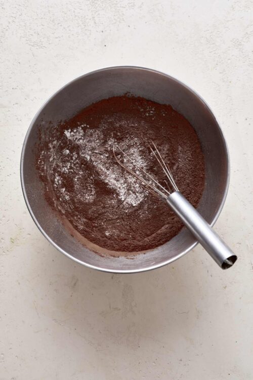 Creamy hot chocolate powder mixture in a metal bowl with a whisk.