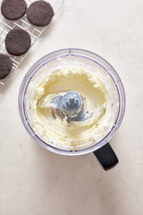 Silky smooth homemade butter in a food processor on a light countertop.