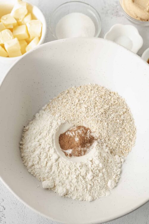 Flour, oats, and spices in a mixing bowl for baking recipes.