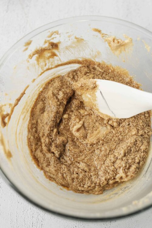 Creamy cinnamon sugar cookie dough mixed in a glass bowl with a spatula.