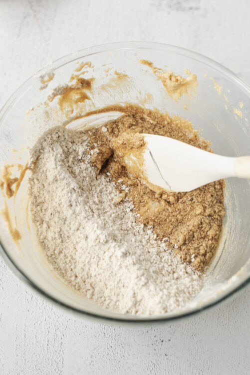 Flour, brown sugar, and butter being mixed for baking recipe in a glass bowl.