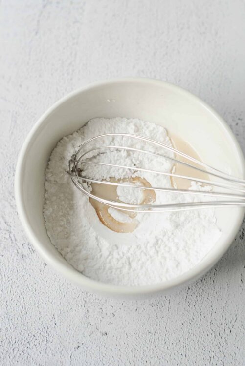 Flour and liquid ingredients in mixing bowl with whisk for baking, baking ingredients, baking at home.