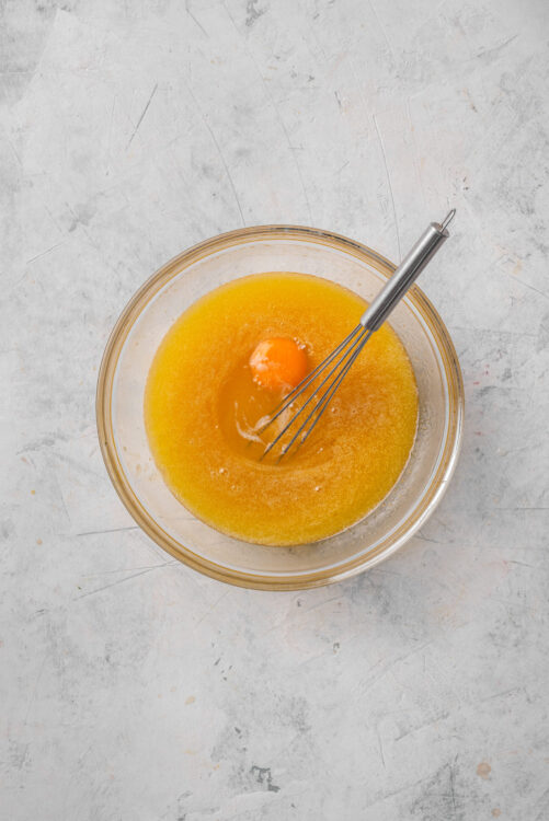 Whisked eggs and melted butter in a glass bowl for baking recipes.