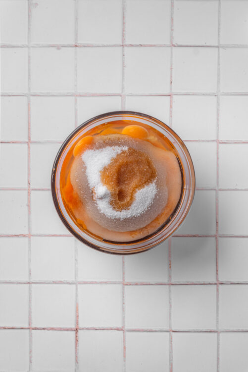 Eggs, sugar, and vanilla in a bowl for baking ingredients preparation.