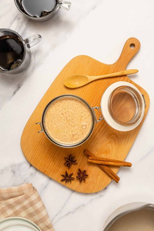 Glasses of black coffee with cinnamon sticks on a marble countertop.