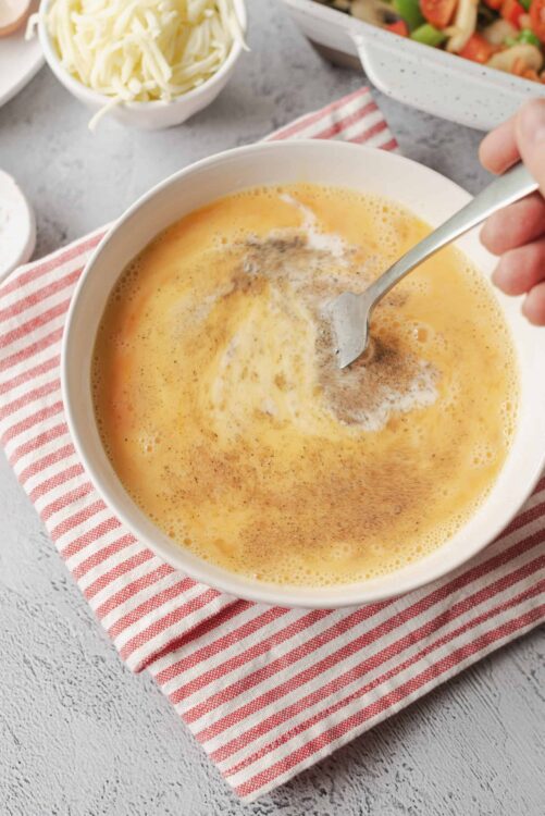 Creamy scrambled eggs with cinnamon, served in a white bowl on a red striped cloth. Perfect for breakfast or brunch.