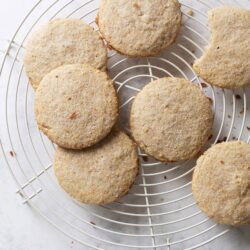 Buttery sugar cookies on a cooling rack with a bite taken out.