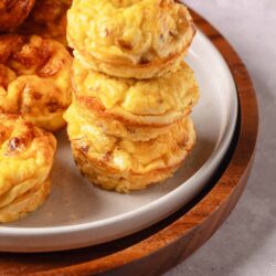 Fluffy homemade cheese muffins on a white plate with wooden tray background.