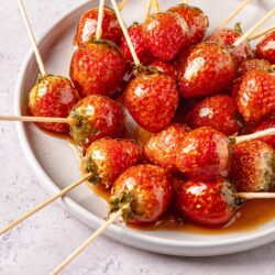 Fresh strawberry caramel lollipops on a white plate, ready to serve.
