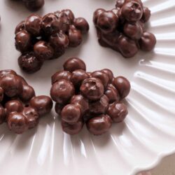 Golden-brown chocolate cluster candies on elegant white serving plate, perfect for holiday treats.