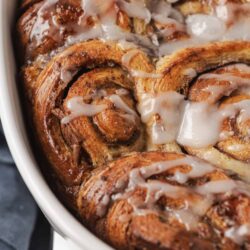 Buttery cinnamon rolls with icing in a baking dish.