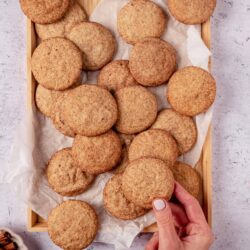 Cinnamon sugar cookies in a wooden tray with parchment paper, close-up of freshly baked treats.