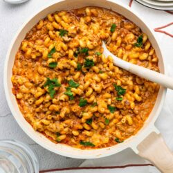 Creamy baked pasta with tomato sauce and cheese in a white skillet.
