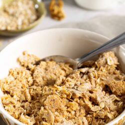 Crunchy homemade oatmeal crumble in a white bowl for baked breakfast or dessert recipes.