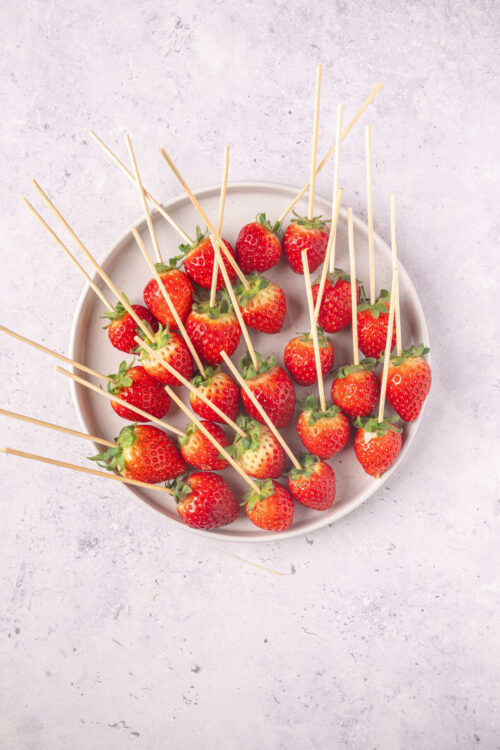 Fresh strawberries with wooden skewers for snacking or dessert.