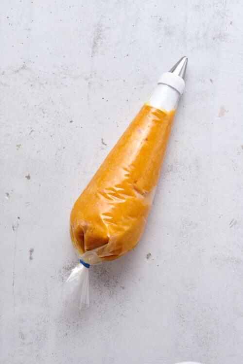 Cream cheese frosting piping bag with yellow frosting, ready for decorating baked goods.