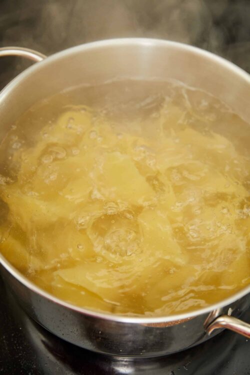 Boiling pasta in a pot on stove for homemade Italian recipes.