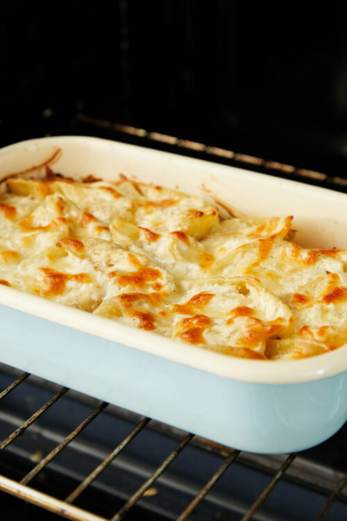 Creamy baked chicken casserole with crispy cheese topping inside oven.