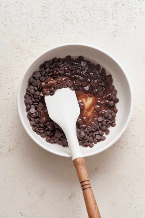 Rich chocolate chips melting in a white bowl for baking recipes.