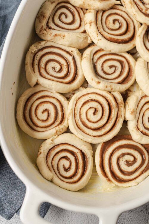 Swirl cinnamon rolls in a baking dish, ready to be baked, featuring soft, flaky dough with cinnamon filling.
