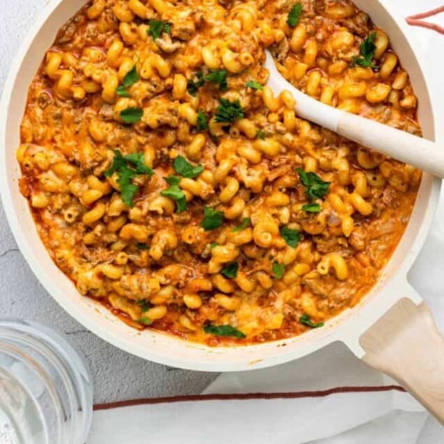 Creamy baked macaroni and cheese in a white skillet with fresh herbs, cheesy and comforting baked pasta dish.