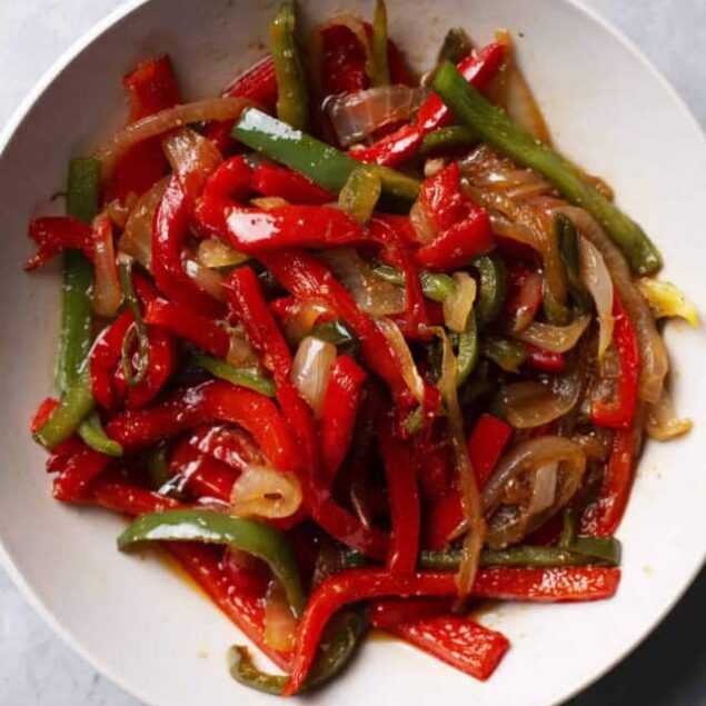 Colorful stir-fried bell peppers and onions in a white bowl, highlighting a healthy vegetable dish.