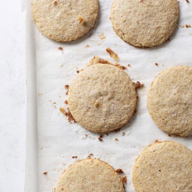 Cornbread cookies with a golden crust and crumbly texture, placed on parchment paper in a baking sheet.