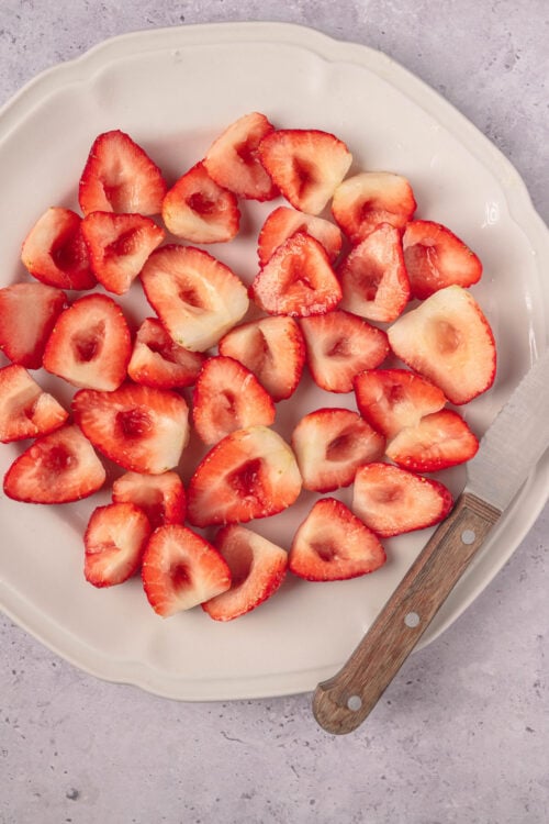 Fresh sliced strawberries on a white platter for baking or snacking.
