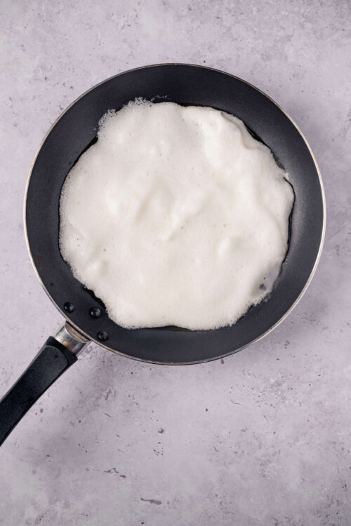 Frying pan with milk and foam for homemade baking or cooking recipes.