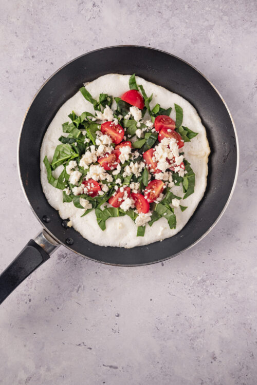 Fresh homemade pizza with cherry tomatoes, basil, and feta cheese on a skillet - Baked Bree recipe inspiration.