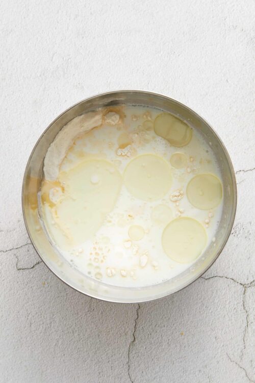 Creamy milk and eggs mixture in a stainless steel bowl ready for baking or cooking.