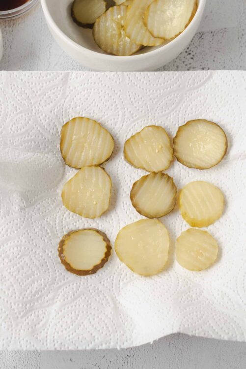 Freshly sliced pickles on a paper towel for homemade pickle chips.