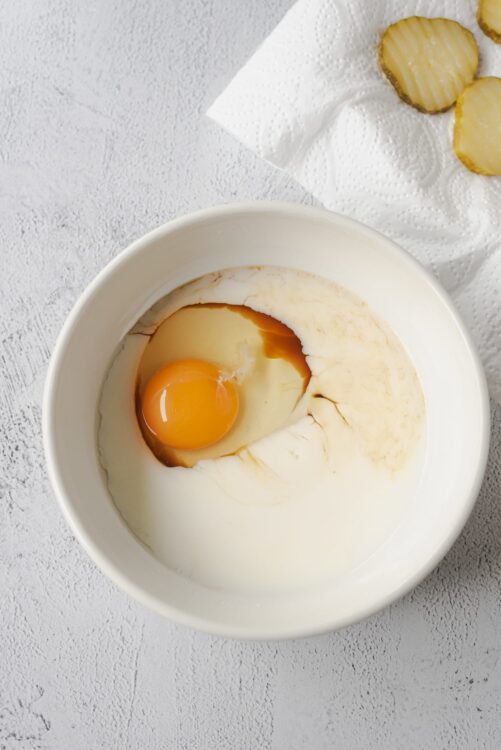 Raw egg in a white bowl with soy sauce, ready for baking or cooking.