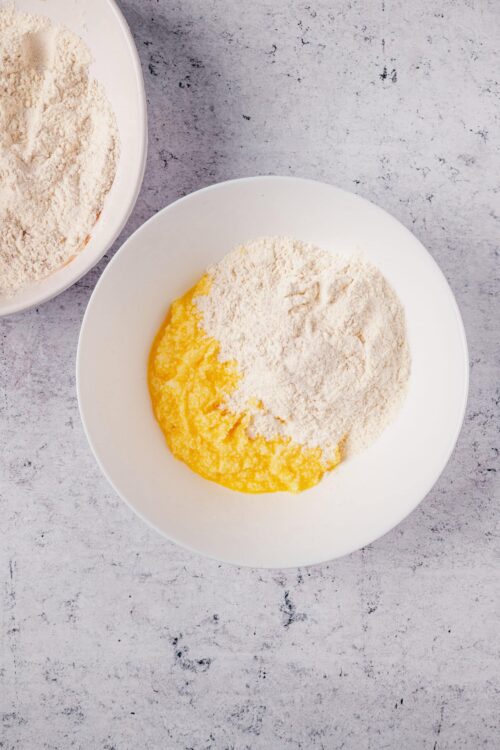 Fine baking ingredients for pie crust, flour, butter, in white bowl on gray surface.