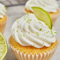 Lemon cupcake with whipped frosting and lime zest garnish.