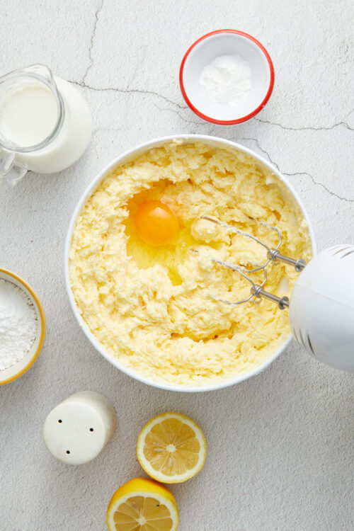 Creamy lemon pound cake batter with fresh lemon halves and baking ingredients.