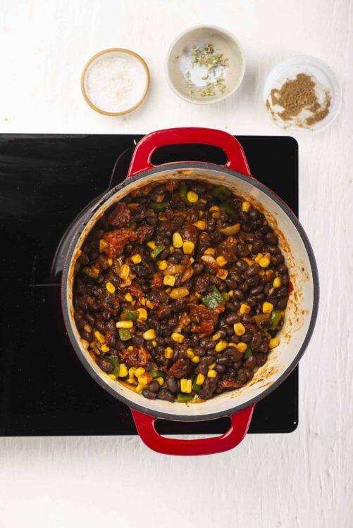 Hearty vegan black bean chili in a red cast iron Dutch oven. Perfect for cozy comfort food and easy dinner recipes.