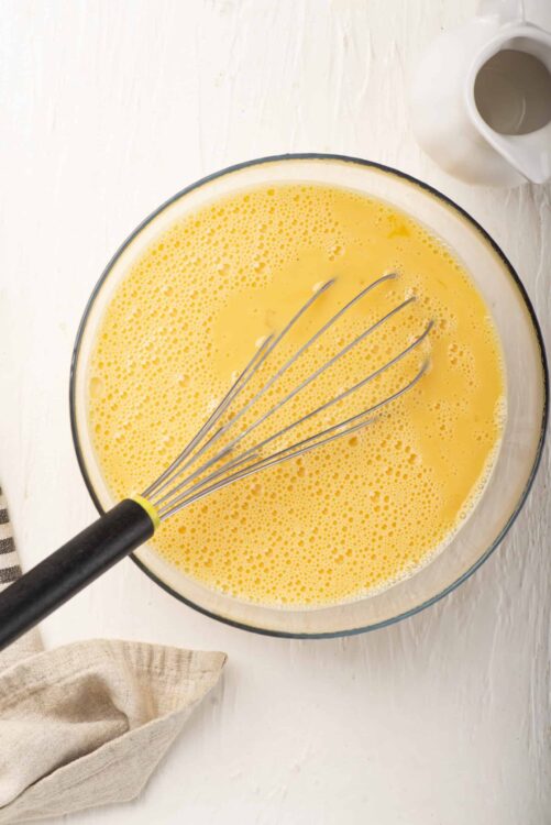 Fluffy beaten eggs in a glass bowl ready for baking or cooking.