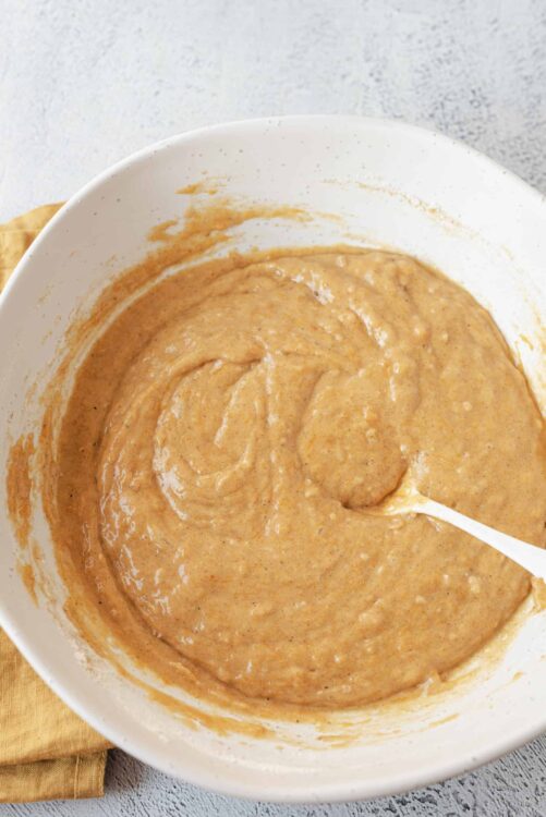 Creamy peanut butter cookie dough in a white mixing bowl with a spatula.