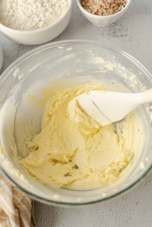 Creamy homemade butter in a glass mixing bowl with a spatula.