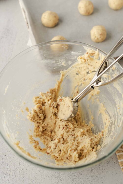 Creamy cookie dough being mixed in a glass bowl with a hand mixer.