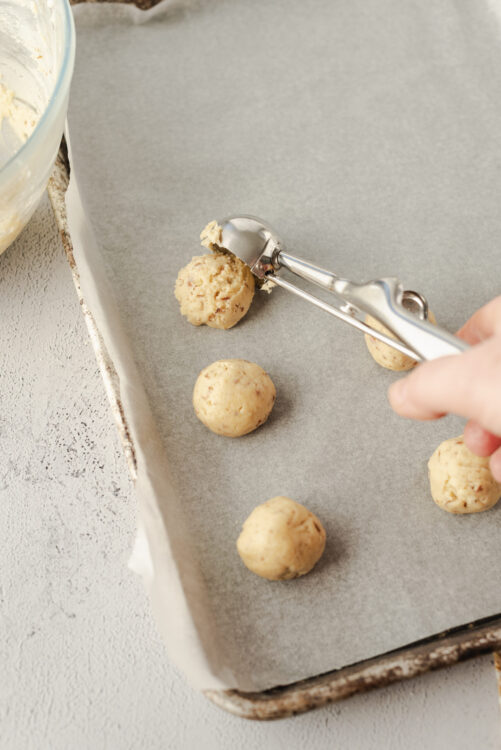 Cream cheese cookie dough balls on baking sheet ready for baking.