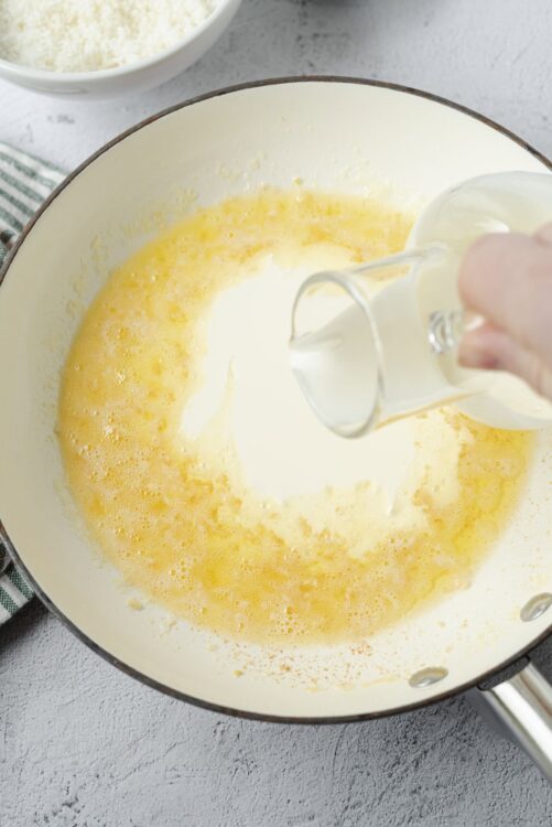 Cream and milk mixture being poured into a skillet for baking or cooking.