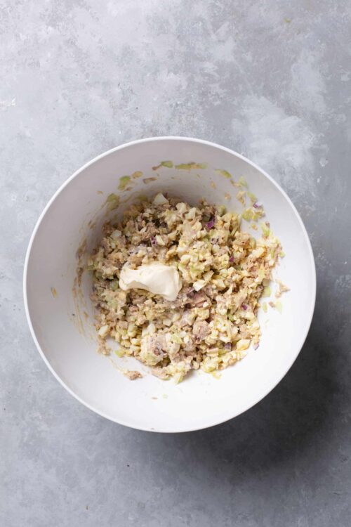 Casserole mixture with cream cheese in a white bowl on gray surface.
